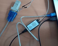 Złącze DB9 połączone z analizatorem logicznym i komputerem przez kable USB na drewnianym blacie.