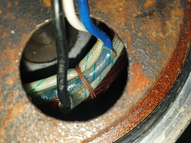 Zbliżenie przewodów elektrycznych w otworze metalowej obudowy.