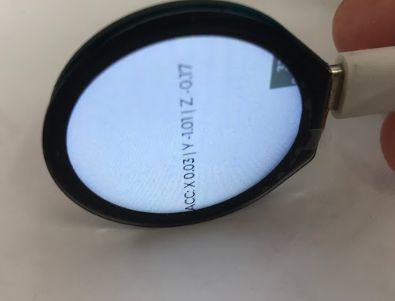 Okrągły ekran LCD ESP32-S3-Touch-LCD-1.28 wyświetlający dane z akcelerometru z jednostką w ręku.