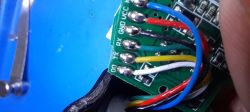 Zbliżenie płytki PCB z przylutowanymi przewodami; widoczne opisy: GND, VCC, RX, TX, DO.