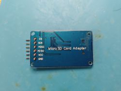 Micro SD card adapter with six pins labeled CS, SCK, MOSI, MISO, VCC, GND