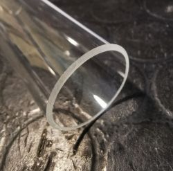 Transparent, sanded tube lying on a dark background.