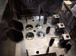 Zbliżenie na wewnętrzną część urządzenia elektronicznego z elementami metalowymi i plastikowymi.