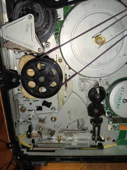 Wnętrze magnetowidu Funai V-3EE z widocznymi kołami zębatymi i paskami.