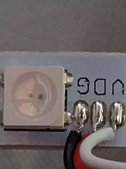 Close-up of an LED on an LED strip with visible soldered wires.