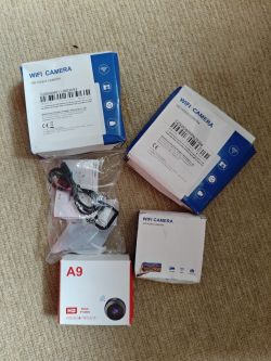 Five WiFi camera boxes, including one labeled model A9, on a beige carpet