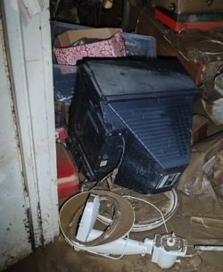 Old CRT device in a flooded room filled with mud and debris.