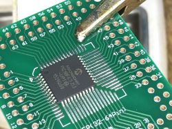 Printed circuit board with a TQFP chip secured by a clip.