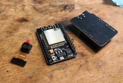 ESP32-Cam with Camera and MB Adapter ESP32-Cam board with OV2640 camera and MB adapter on a wooden surface.