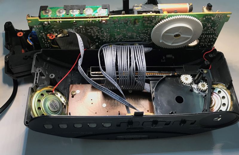 Wnętrze rozebranego radiobudzika z widoczną elektroniką, głośnikiem i przekładniami zębatymi