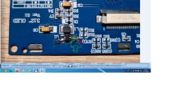 Close-up of a blue PCB with SMD parts and handwritten markings indicating a 10-ohm resistor