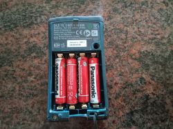 Widok na tył dalmierza laserowego Bosch z otwartą komorą baterii, zawierającą cztery baterie AAA.