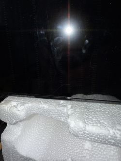 Light reflecting on a dark screen with a piece of white styrofoam below.