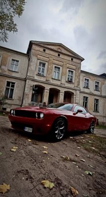 Red sports car parked in front of an old, rundown building.