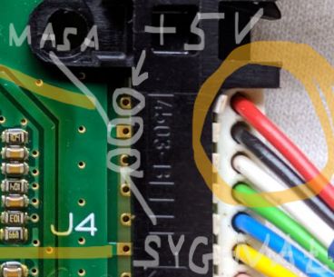 Close-up of a circuit board with an edge connector and marked wires.