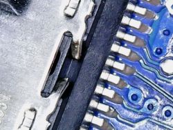 Zbliżenie uszkodzonego gniazda USB-C na niebieskiej płytce PCB