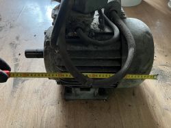 Zdjęcie pokazuje silnik elektryczny mierzony taśmą mierniczą po długości.