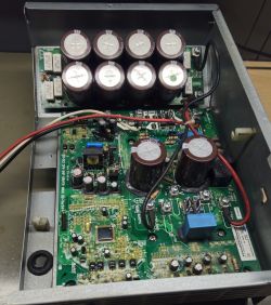Widok na płytę falownika pompy ciepła z widocznymi kondensatorami i innymi elementami elektronicznymi.