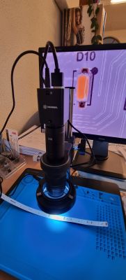 TechReal digital microscope positioned over a blue mat on a desk in an office.