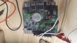 Zbliżenie na płytkę drukowaną z różnymi komponentami elektronicznymi, przewodami i diodami na drewnianym tle.