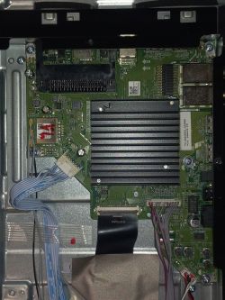 Zbliżenie na płytę główną z widocznymi komponentami elektronicznymi i podłączonymi kablami.
