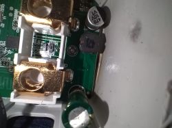 Close-up of electronic components, including brass terminals and a capacitor on a PCB.