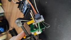 Electronic module held by clamp, connected with wires to Arduino board