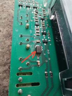 Zbliżenie zielonej płytki PCB z elementami SMD; czerwona strzałka wskazuje czarny układ.