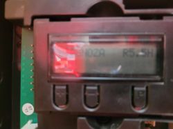 Zbliżenie na wyświetlacz LCD w panelu sterującym z widocznymi przyciskami.