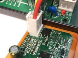 Zbliżenie na płytkę drukowaną stacji lutowniczej z widocznymi elementami elektronicznymi, złączem i przewodami.