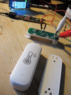 TH01 Temperature and Humidity Sensor with Test Wires TH01 temperature and humidity sensor with attached test wires on a wooden table next to the casing.