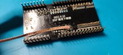 ESP-12F board during soldering process with visible copper braid.
