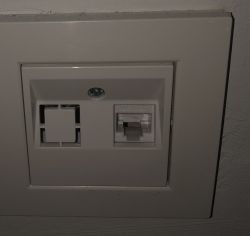 Gniazdo ścienne z jednym portem sieciowym RJ-45 i zaślepką.