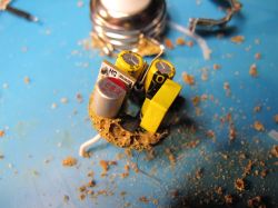 Interior of an electronic module with visible capacitors and brown residue, likely a damaged LED bulb circuit.