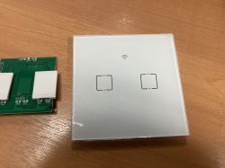 View of a disassembled two-gang touch switch and its casing on a desk.