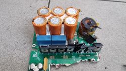 Rozebrana ładowarka OBC z samochodu elektrycznego z widocznymi kondensatorami i komponentami.