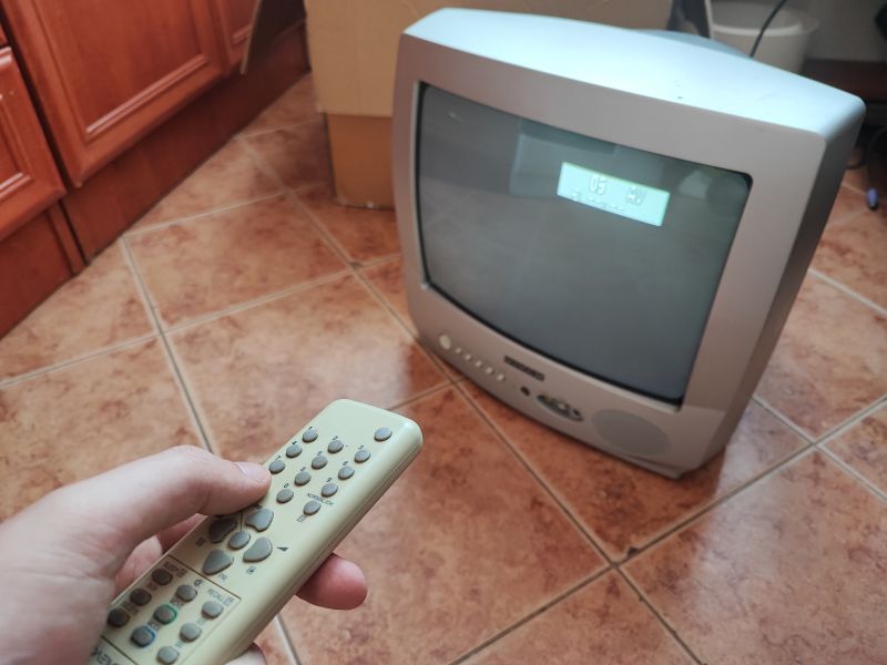 Telewizor kineskopowy Daewoo K14C5GT z wyświetlaczem oraz pilotem, ustawiony na podłodze w kuchni.