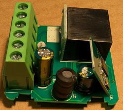 Close-up of an electronic module with capacitors, coil, and screw terminal block