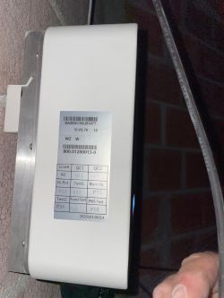 Close-up of an electronic device with a label showing serial numbers and test designations.