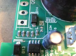 Zbliżenie na płytkę drukowaną z widocznymi elementami elektronicznymi, takimi jak rezystory i diody.