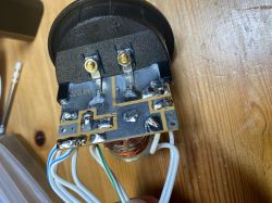 Zbliżenie na płytkę drukowaną z elementami elektrycznymi oraz przewodami, na drewnianym stole.