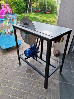 Stół z zamontowaną tarczą tnącą marki Drel i niebieskim silnikiem elektrycznym pod spodem.