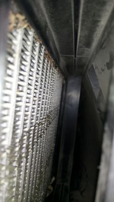 Zbliżenie na metalowy parownik samochodowej klimatyzacji z widocznymi oznakami rdzy i zabrudzeń.