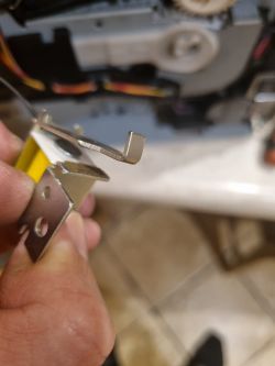 Zbliżenie dłoni trzymającej metalowy element z dźwignią i podkładką filcową z drukarki