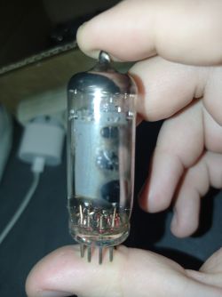 Lampa elektronowa typu noval trzymana w ręce, z ośmioma nóżkami i lekko widocznymi oznaczeniami.