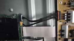 Zbliżenie na wnętrze telewizora Samsung z widocznymi taśmami i płytą PCB