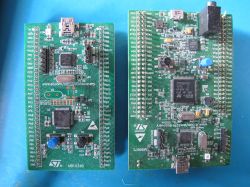 Two STM32 development boards with microcontrollers and connectors on a blue background.