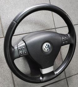 Czarna kierownica samochodowa Volkswagen z przyciskami.