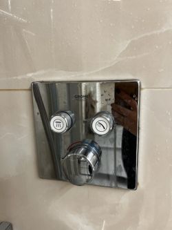 Bateria prysznicowa marki Grohe z trzema pokrętłami na ścianie.