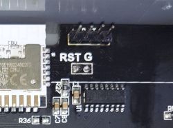 Close-up of a PCB showing “RST G”, a pin header, and SMD components